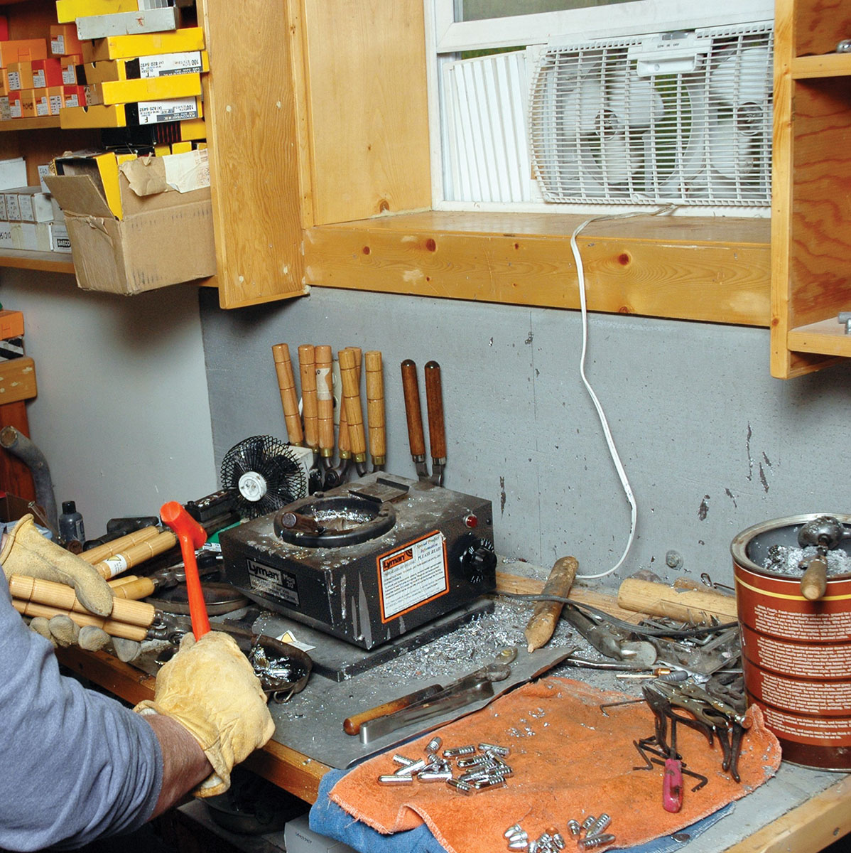 This is Mike’s casting area. Note the orange dead blow hammer, folded towels for cushioning fresh cast bullets with an assortment of small tools, a manicurist fan to the left and an exhaust fan in window.
